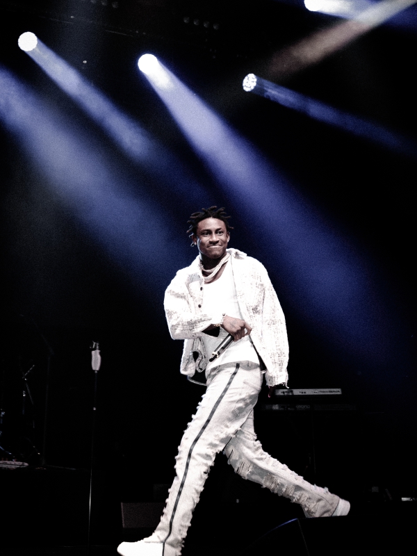 Shallipopi in an all-white tracksuit dancing across the stage under bright white spotlights. — concert photography London by Lamss Media